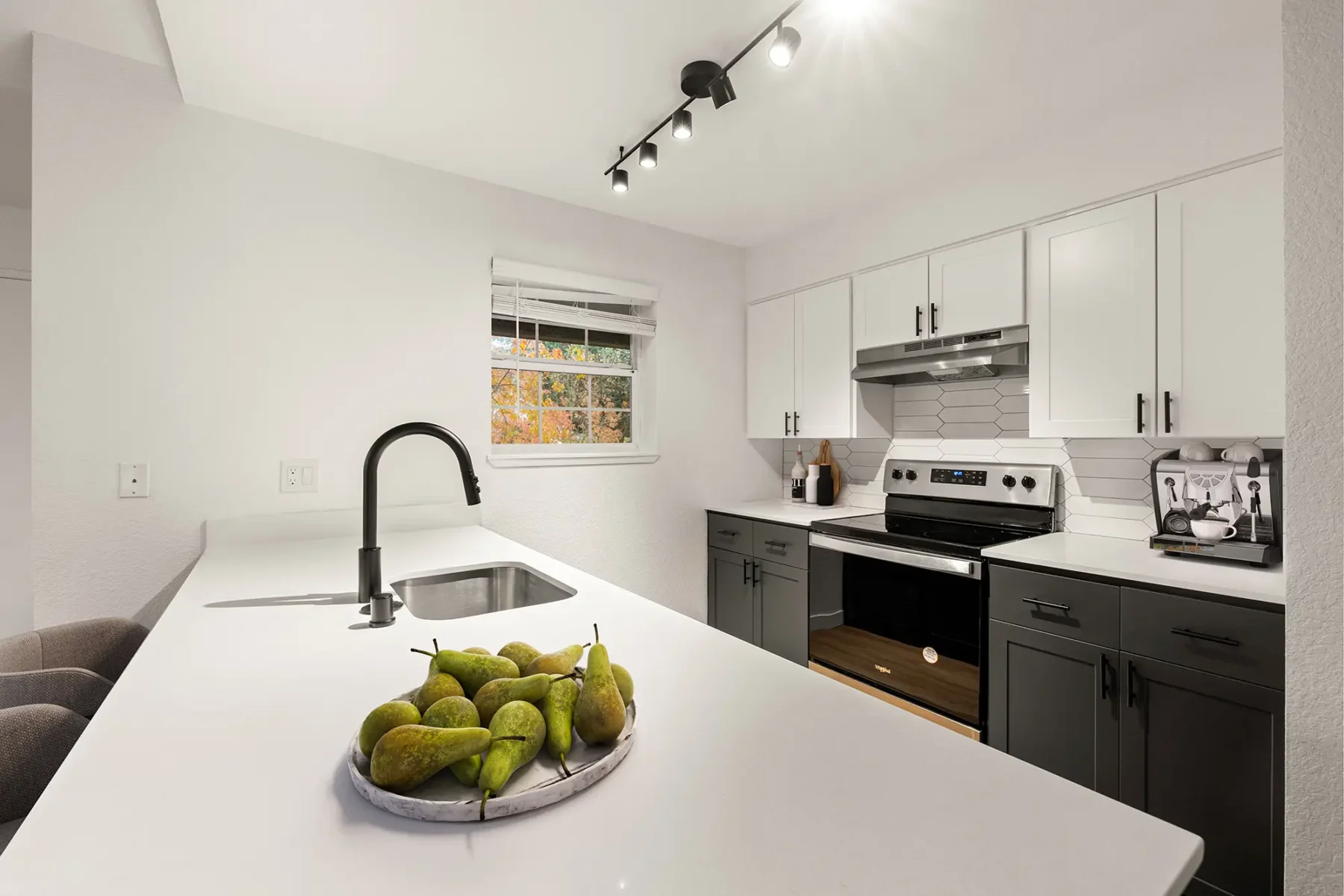 Kitchen with white countertops, stainless appliances, bar height seating at Larkspur Place apartments in Vancouver